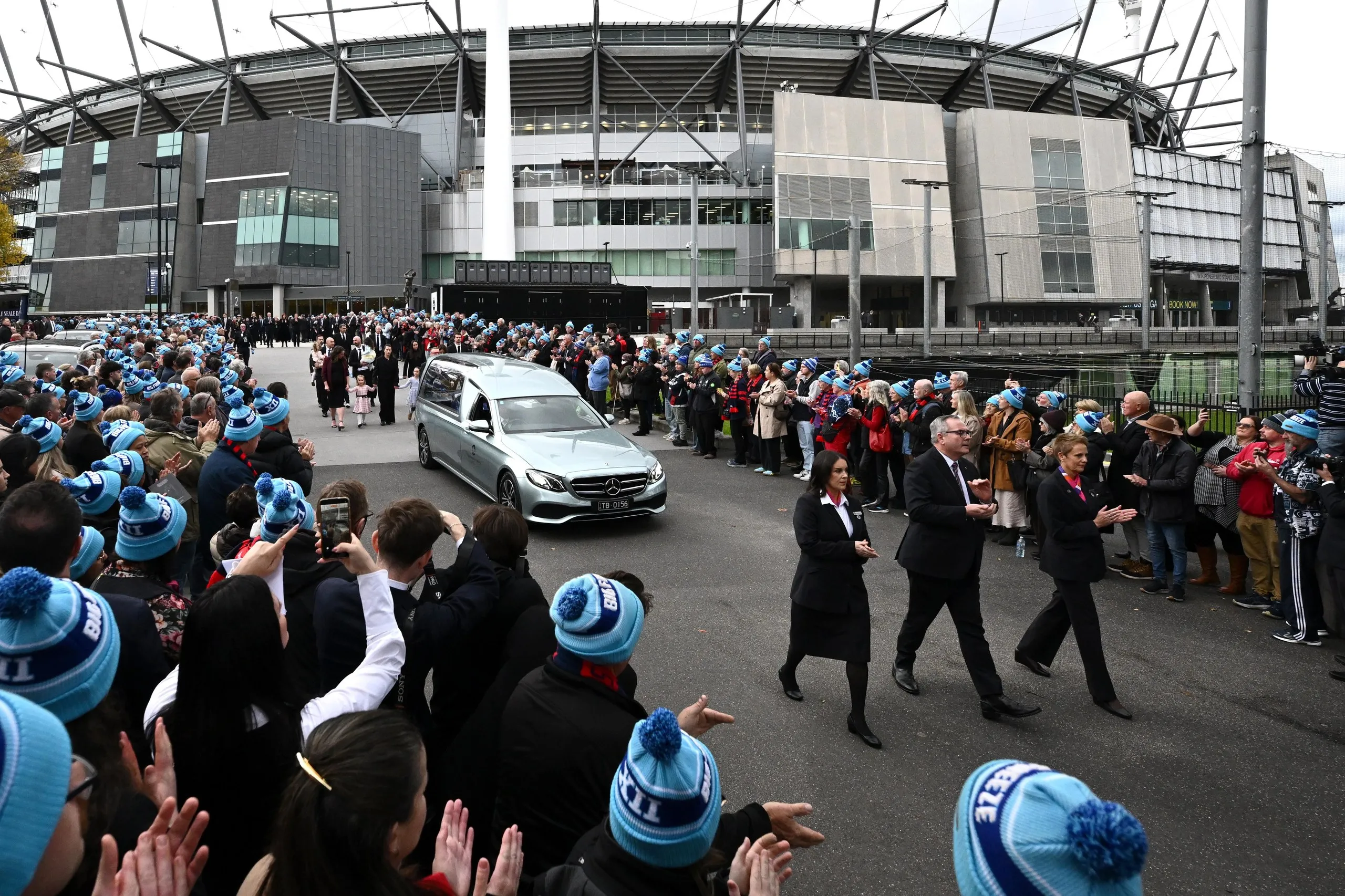 Guests form a guard of honour as the hearse leaves the funeral service for Neale Daniher at the MCG.