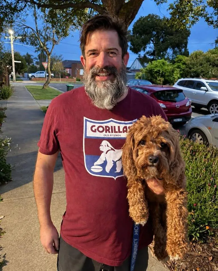 Scott Fletcher wearing a Gorillas shirt – the mascot of Fitzroy until they changed to the Lions in 1957 – with Louis the Cavoodle.